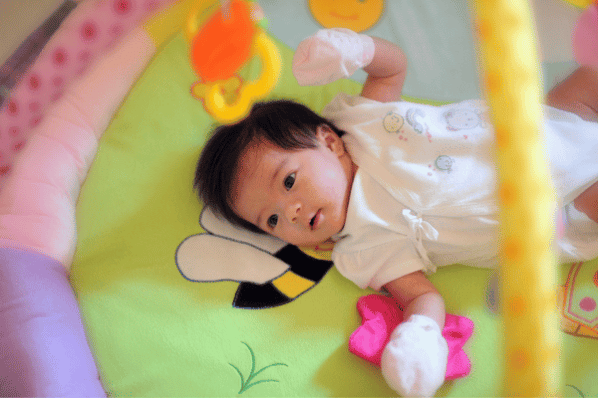 Baby lying on their back looking up at an activity mat.