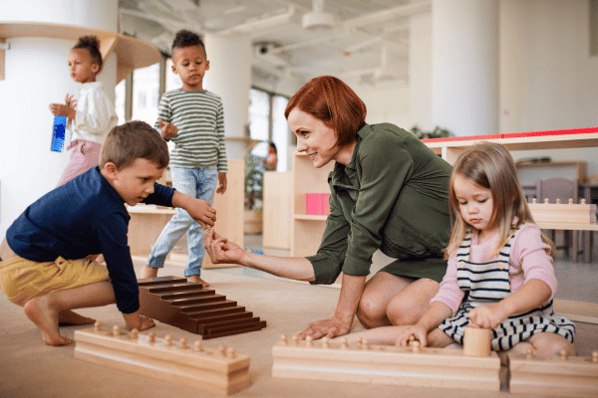 Group of children at daycare building blocks with teacher.