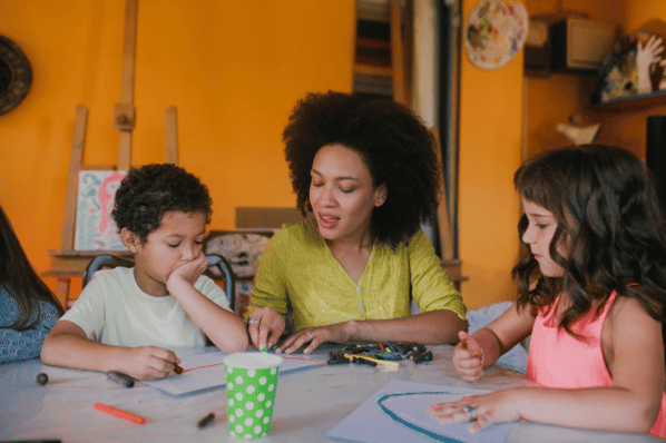 Teacher helping children color in classroom