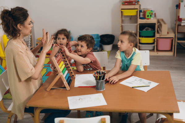 Children learning to count at preschool with teacher.