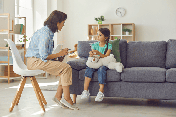 female mental health professional talking to a young preschool girl in a bright office