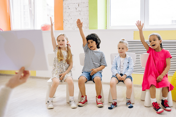 Children raising their hands in class