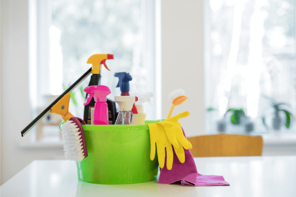 Bucket of cleaning supplies sitting on a desk.