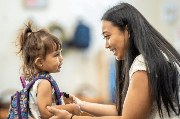 woman with young girl wearing a backpack at daycare drop off