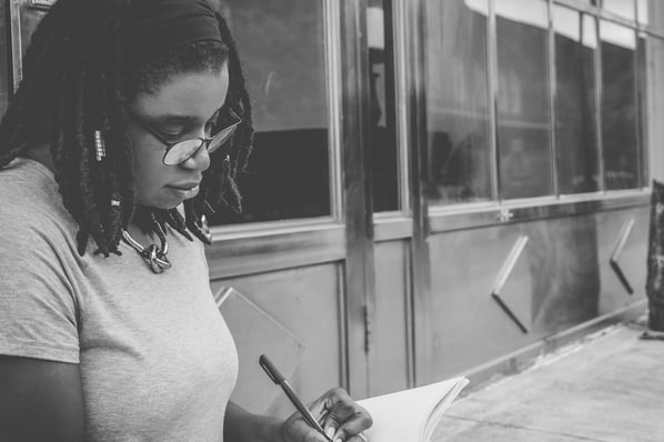 Woman sitting and writing in a notebook.