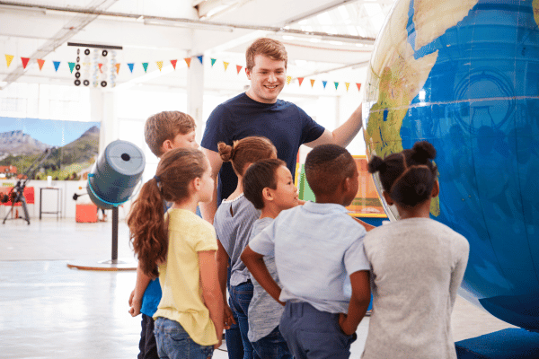 preschool children with teacher at science center looking at a large globe of the earth