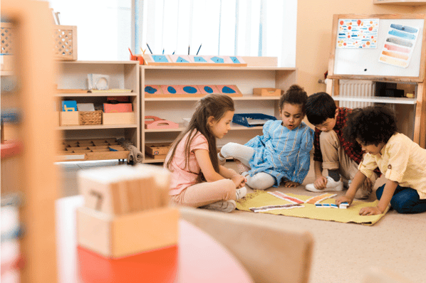 Group of preschool children playing game on floor in montessori classroom