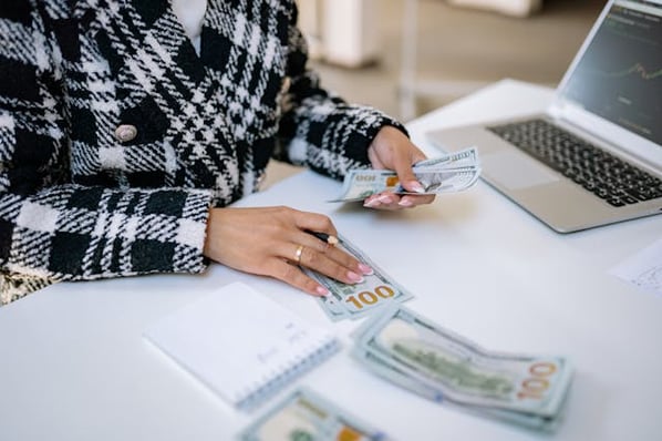 Woman sitting at desk counting $100 bills