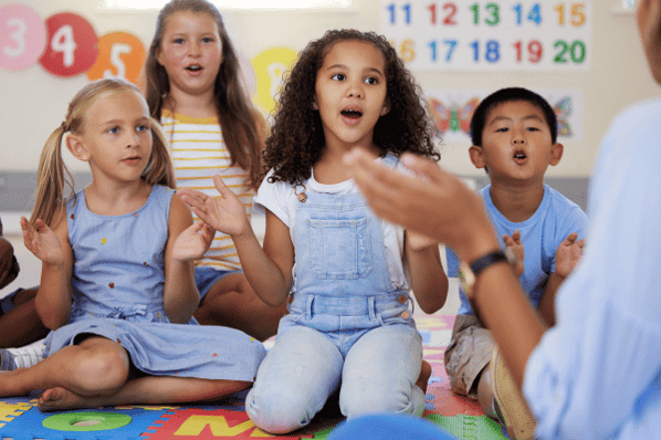 Teacher leading preschool children in a sing-a-long.