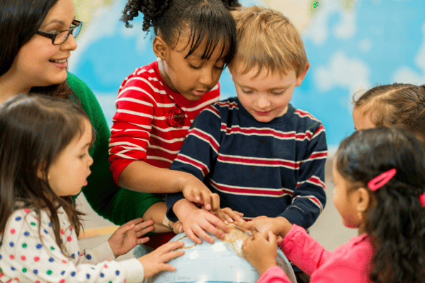 Group of preschool children with teacher looking at and touching a globe.