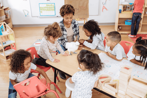 Teacher doing arts and crafts project with preschool children in the classroom.