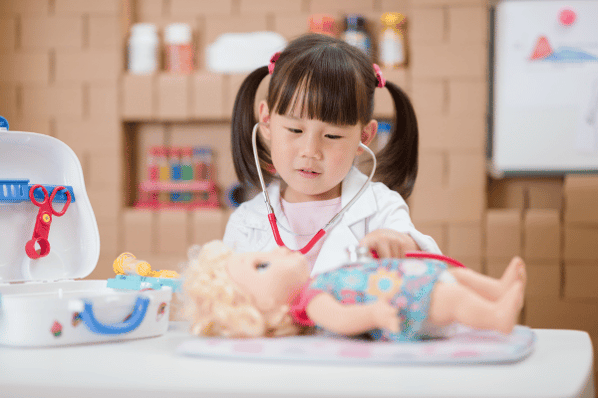 Young girl playing pretend doctor with a doll.