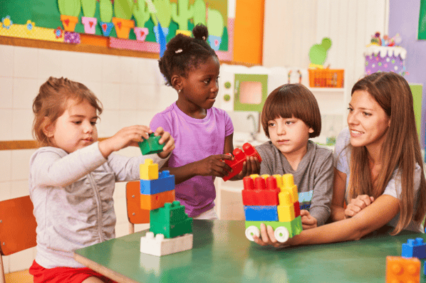 Teacher and children play with colorful building blocks.