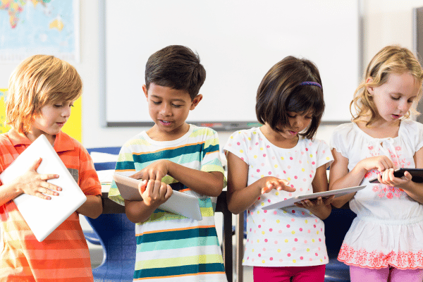 four children using digital tablets in the classroom